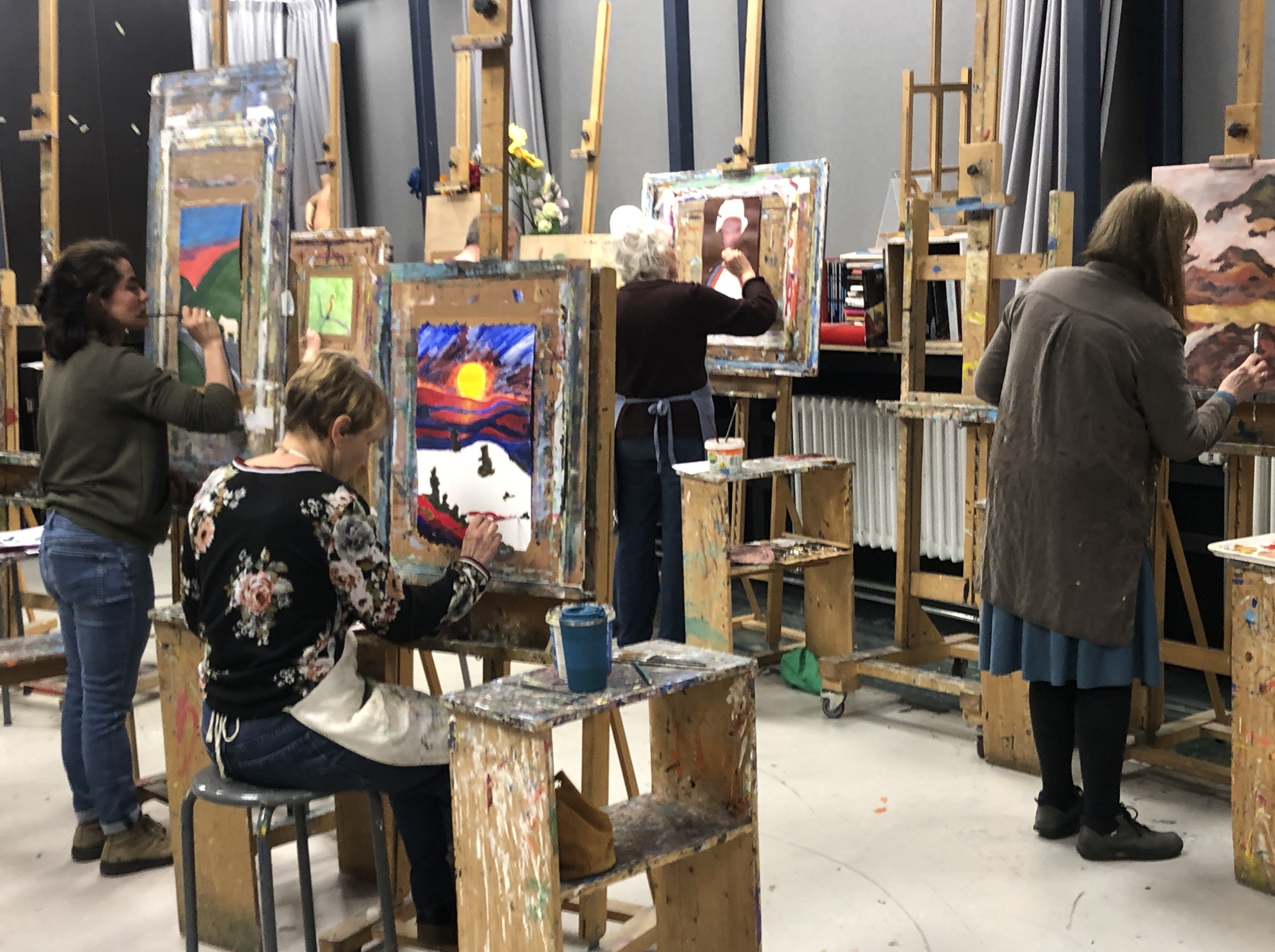 Cursisten werken aan schilderijen in het atelier