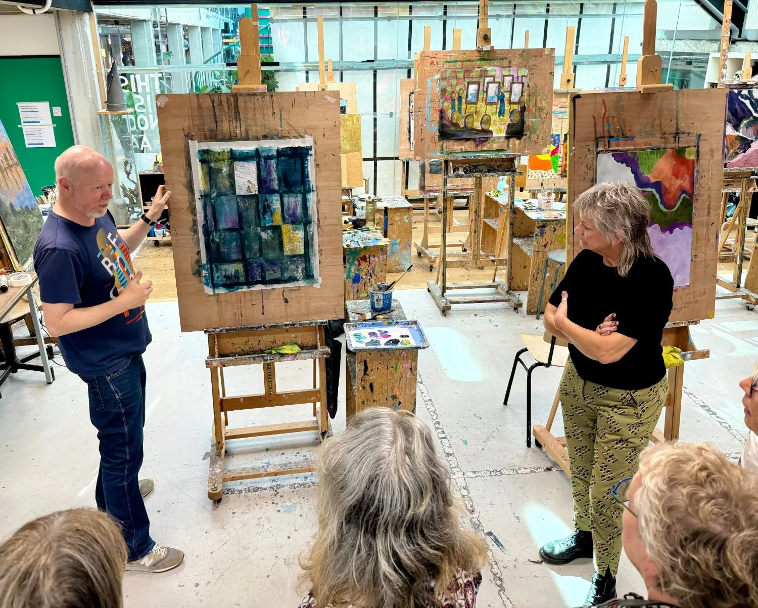 Machiel van Soest bespreekt een schilderij met cursisten in het atelier